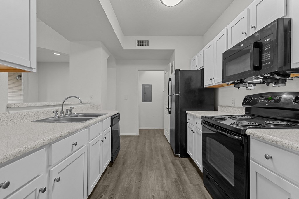 A kitchen with black appliances and white cabinets.