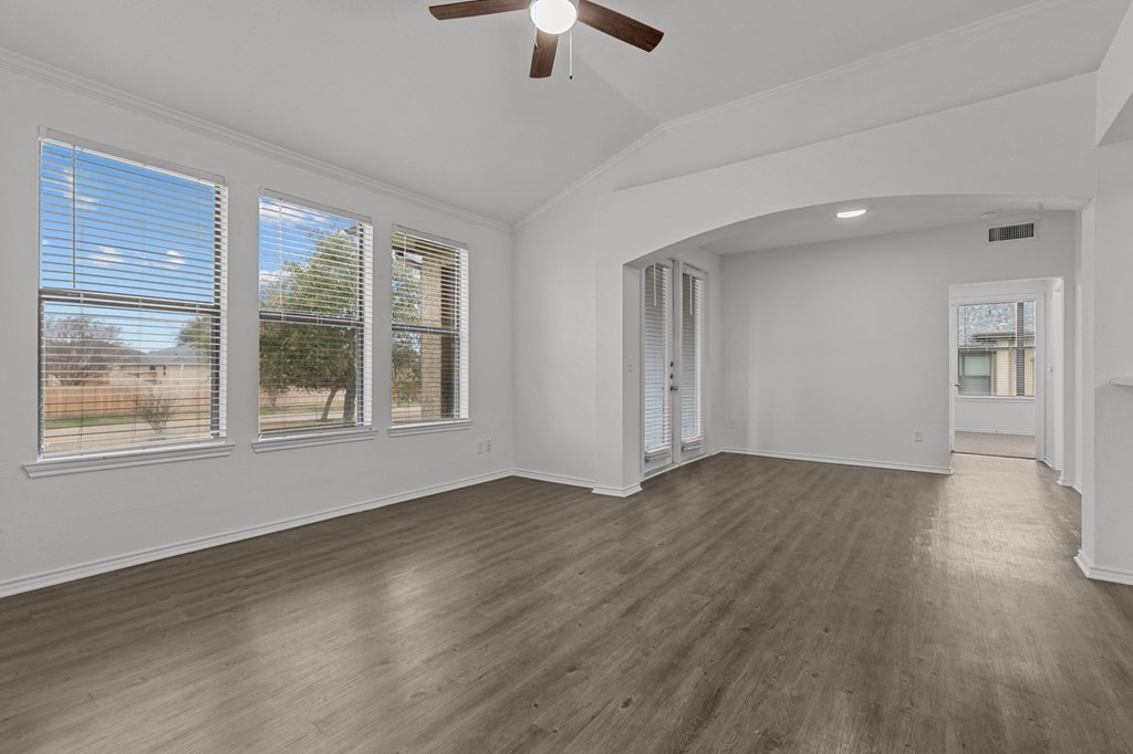 A room with a ceiling fan and wooden flooring.