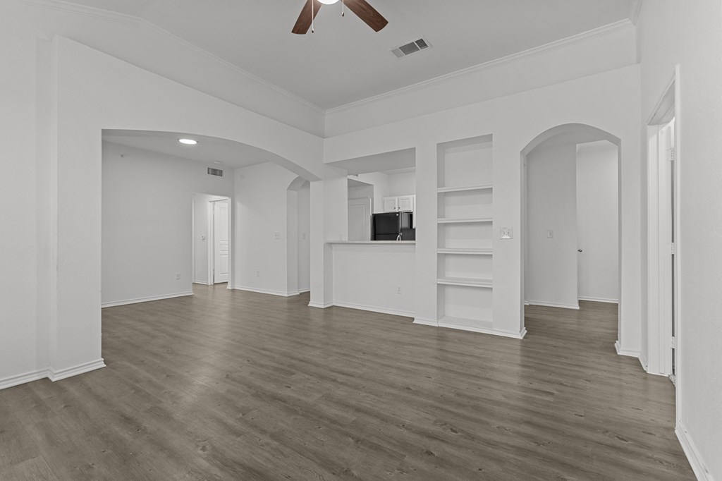 A spacious room with a ceiling fan and wooden flooring.