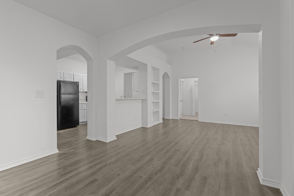 A spacious room with wooden flooring and white walls.