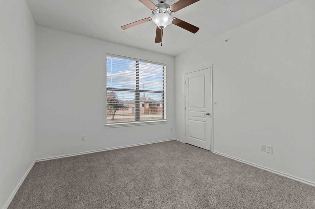 A room with a ceiling fan and a window with blinds.