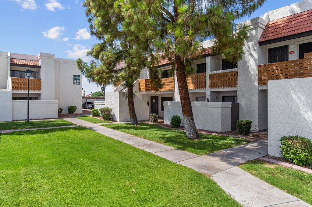 a white building with a lawn and trees in front of it
