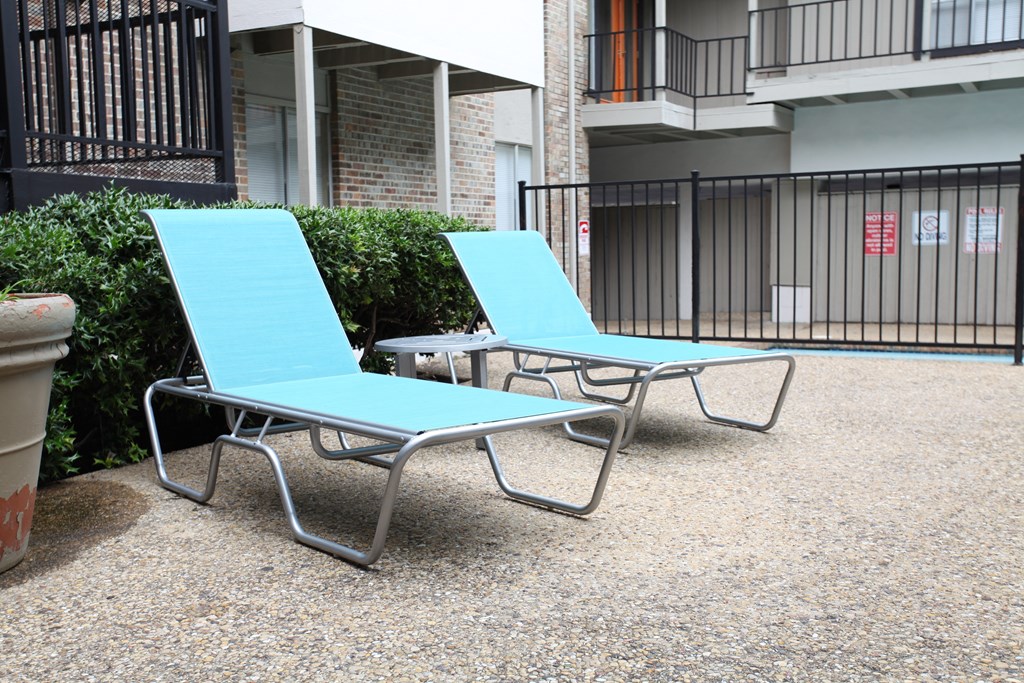 two blue lounge chairs and a table in front of a building