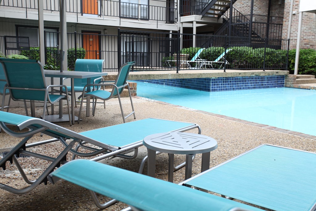 a patio with tables and chairs next to a swimming pool