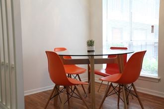 a dining room with a table and four orange chairs