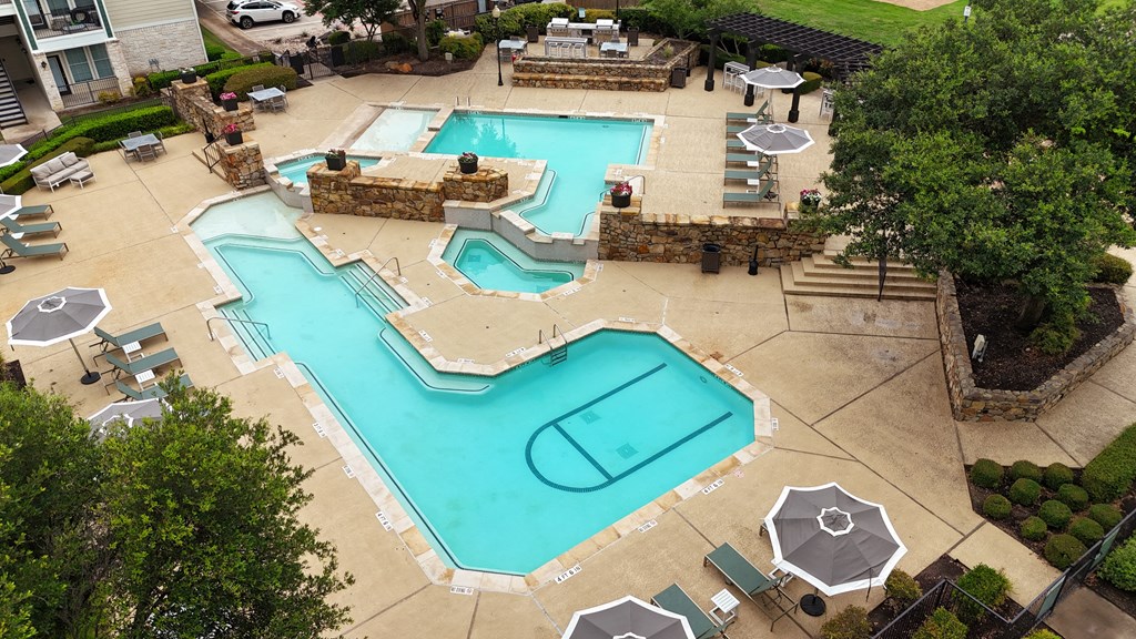 a pool and spa are shown in a backyard with tables and umbrellas