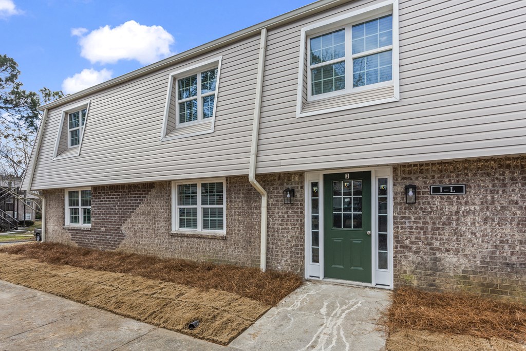 the front of a brick house with a green door