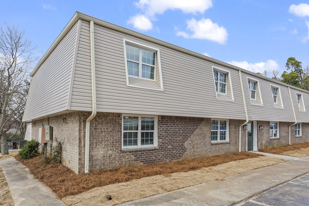 an exterior view of a gray house with brick and siding