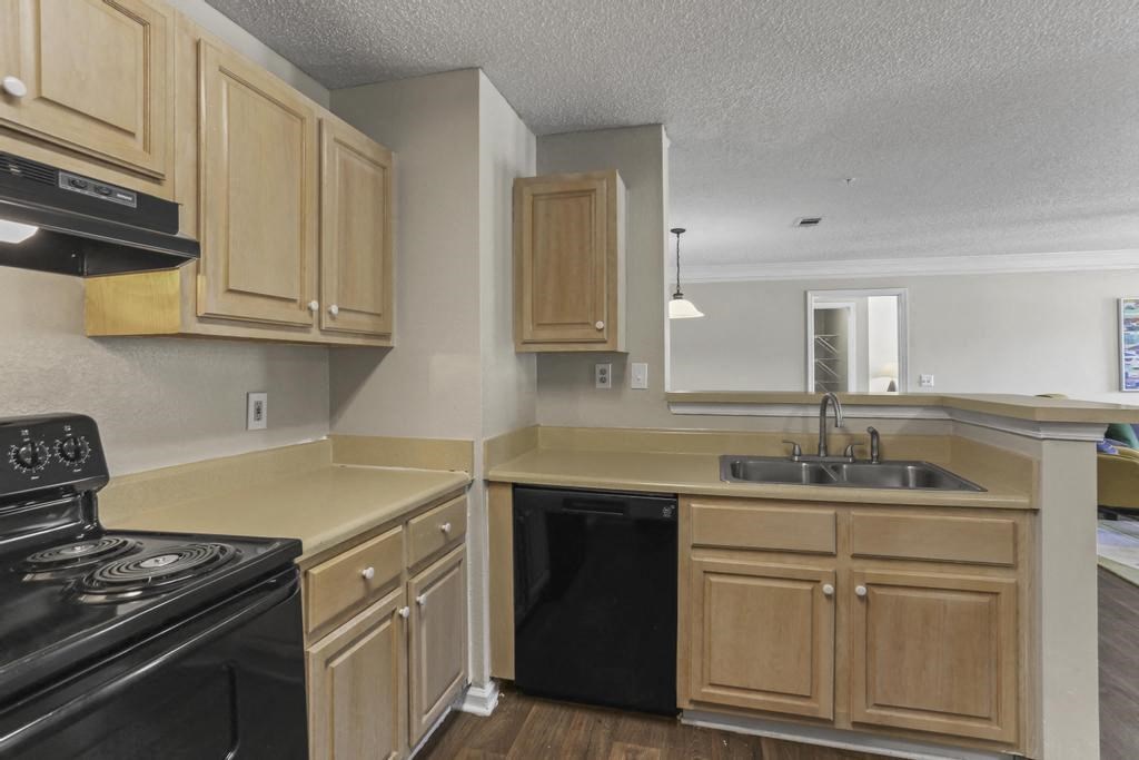 an empty kitchen with wooden cabinets and black appliances