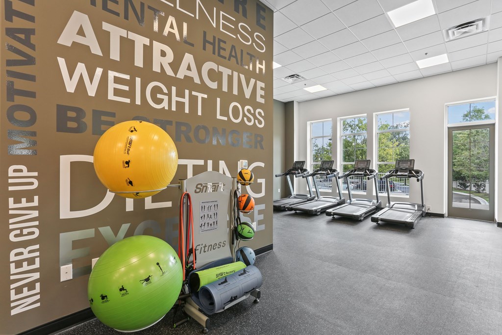 A gym with treadmills, exercise balls, and a wall with fitness-related words.