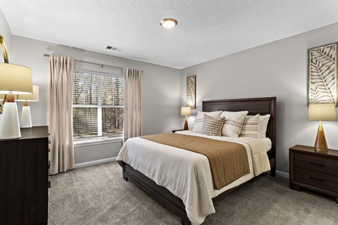 A bedroom with a large bed and a window with curtains.