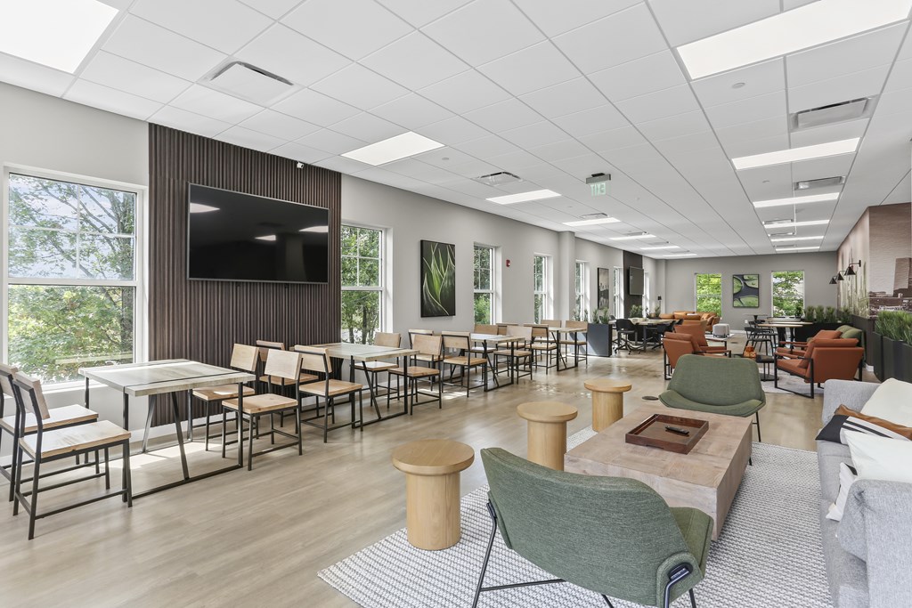 A modern room with a long table and chairs, a television, and a large window.