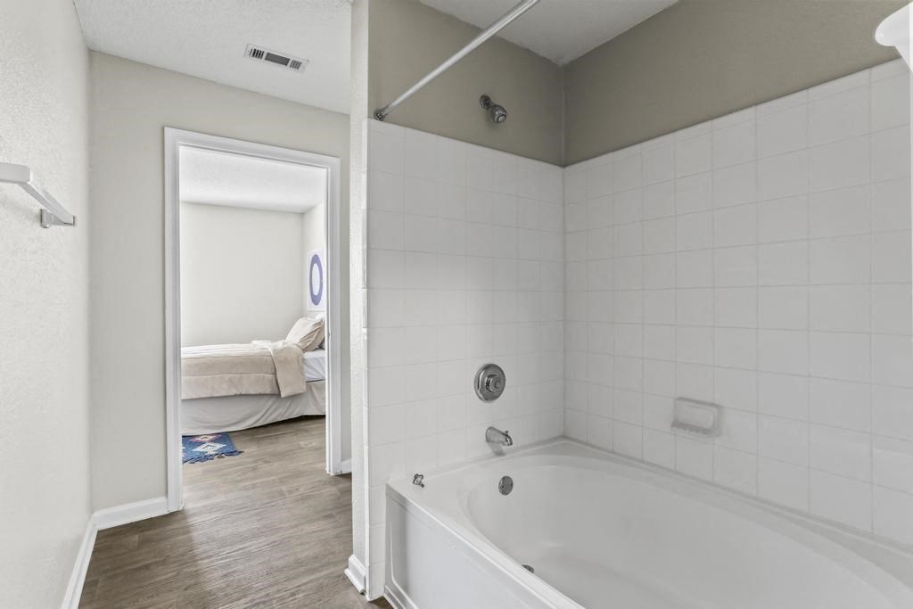 a white bathroom with a tub and a bedroom