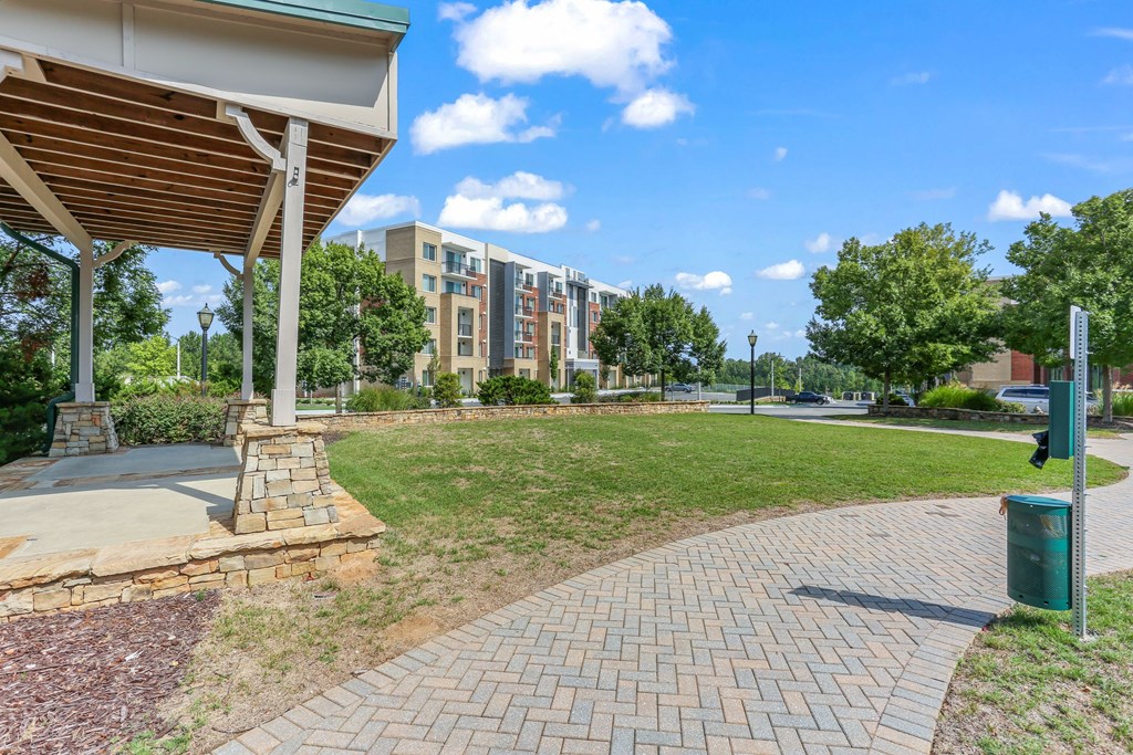 A walkway with a green trash can and a white building in the background.