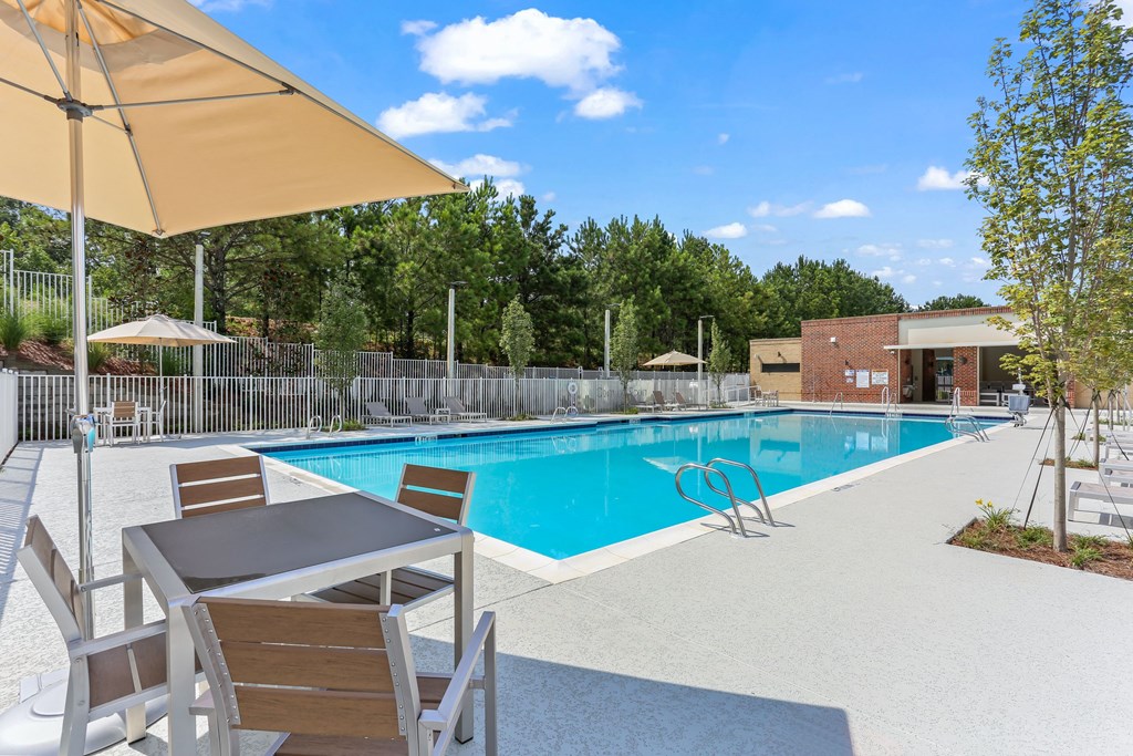 A pool with a table and chairs and an umbrella.