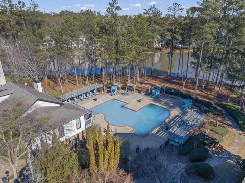 an aerial view of a pool and a house near a lake