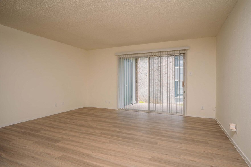 the living room of an empty house with wood floors and a window