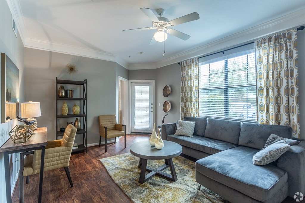 A living room with a grey couch, a wooden coffee table, and a ceiling fan.