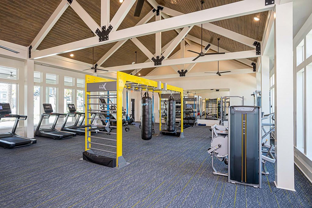 a gym with cardio equipment and weights in a building with windows