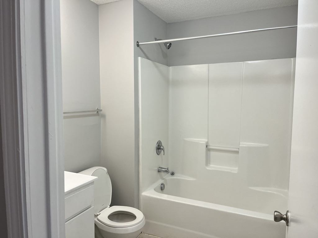 a white bathroom with a toilet and a tub and a sink