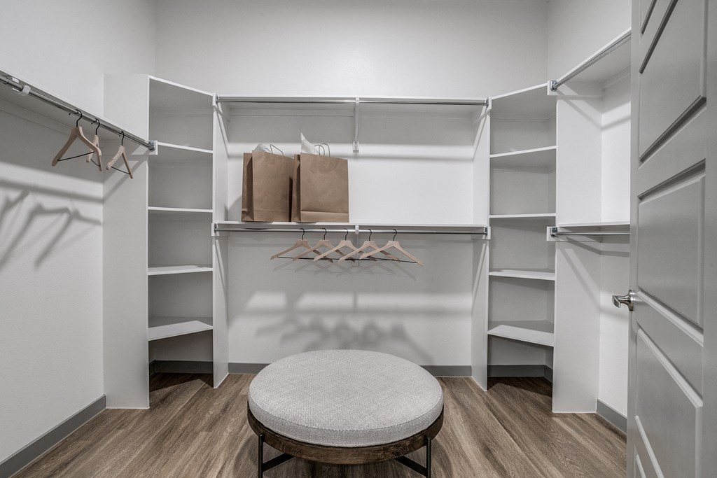 a walk in closet with a round stool in the middle