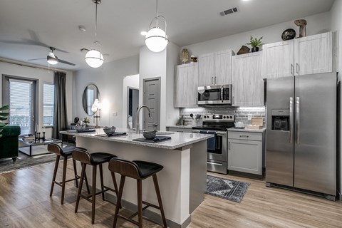 a kitchen with stainless steel appliances and a large island with bar stools