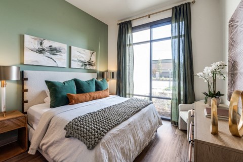 A bedroom with a large bed and a window with curtains.