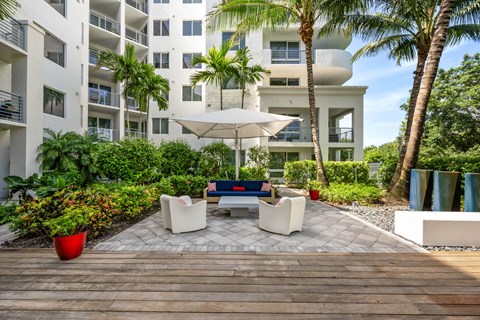 a patio with a table and chairs in front of an apartment building