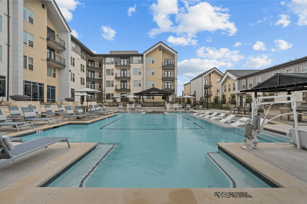 A large indoor swimming pool with lounge chairs and apartment buildings in the background.
