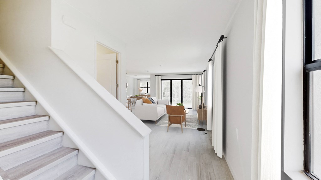 a living room and staircase with white walls and floors and a white couch