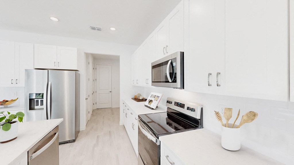 a white kitchen with stainless steel appliances and white cabinets