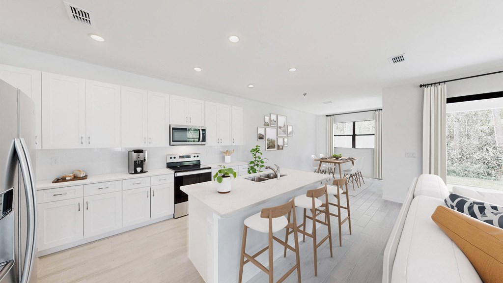 a white kitchen with a large island and a dining table