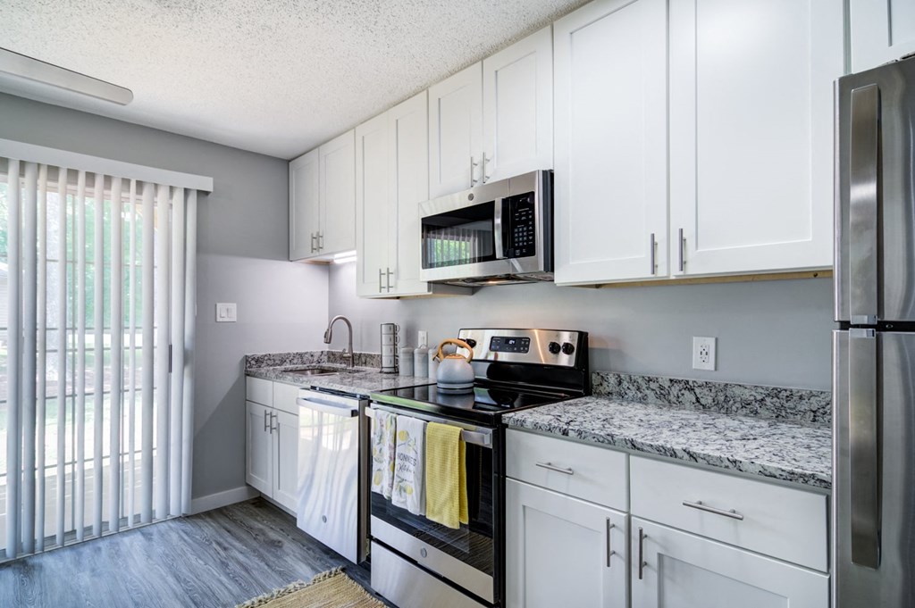 a renovated kitchen with white cabinets and granite countertops