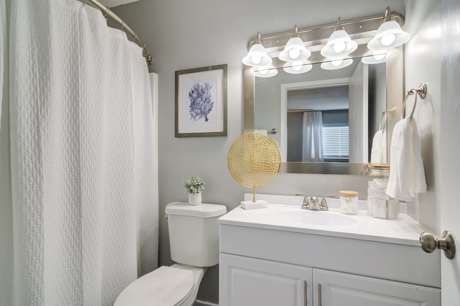 a renovated bathroom bathroom with a white shower curtain and a white toilet next to a white sink with a