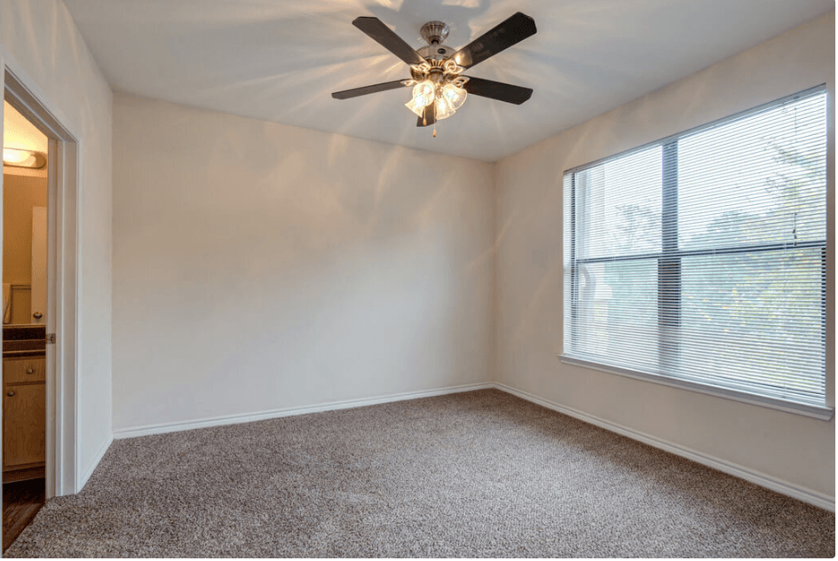 a bedroom with a large window and a ceiling fan