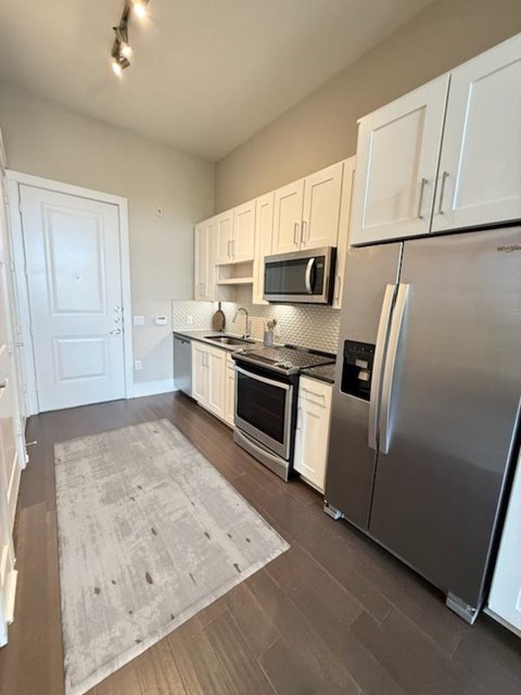 A kitchen with a refrigerator, oven, and microwave.