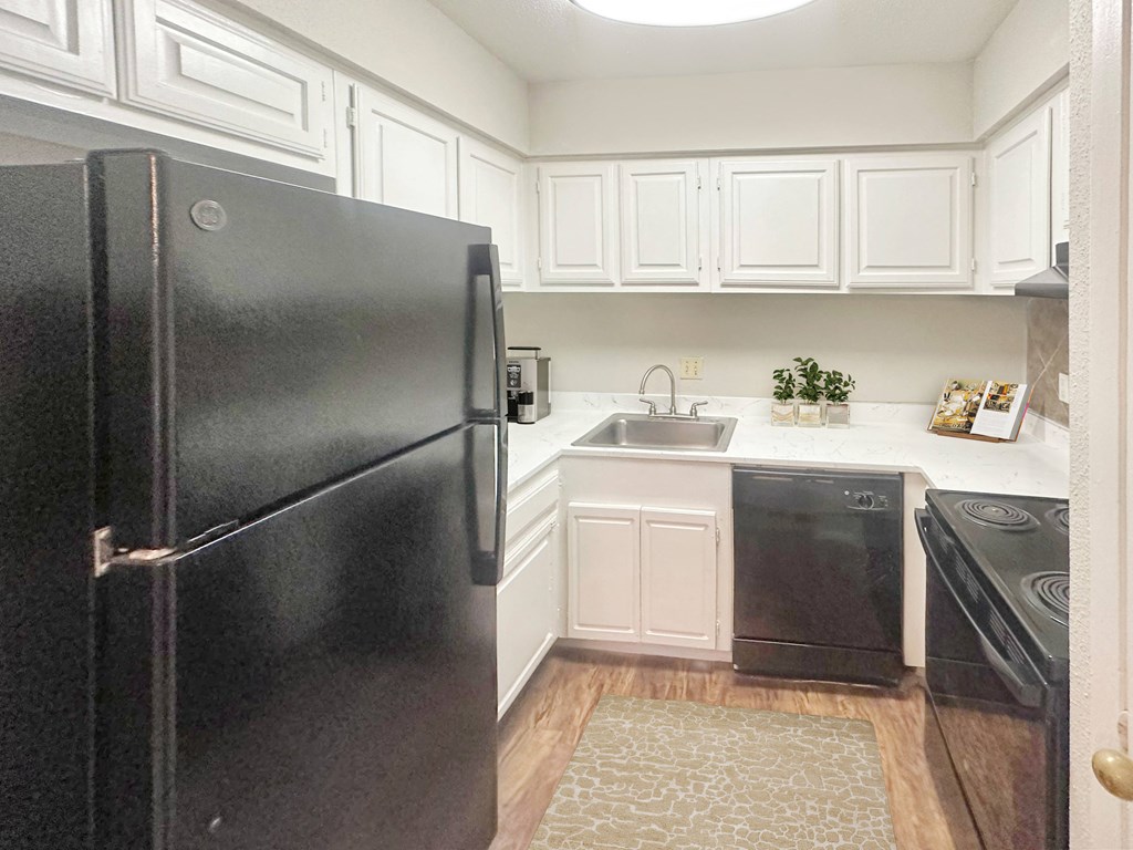 a kitchen with white cabinets and a black refrigerator
