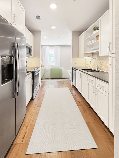 A kitchen with a white refrigerator and white cabinets.