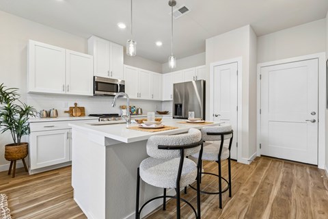 A kitchen with white cabinets and a wooden floor.