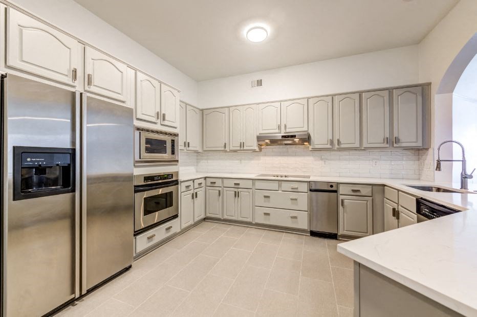 a large kitchen with stainless steel appliances and white cabinets