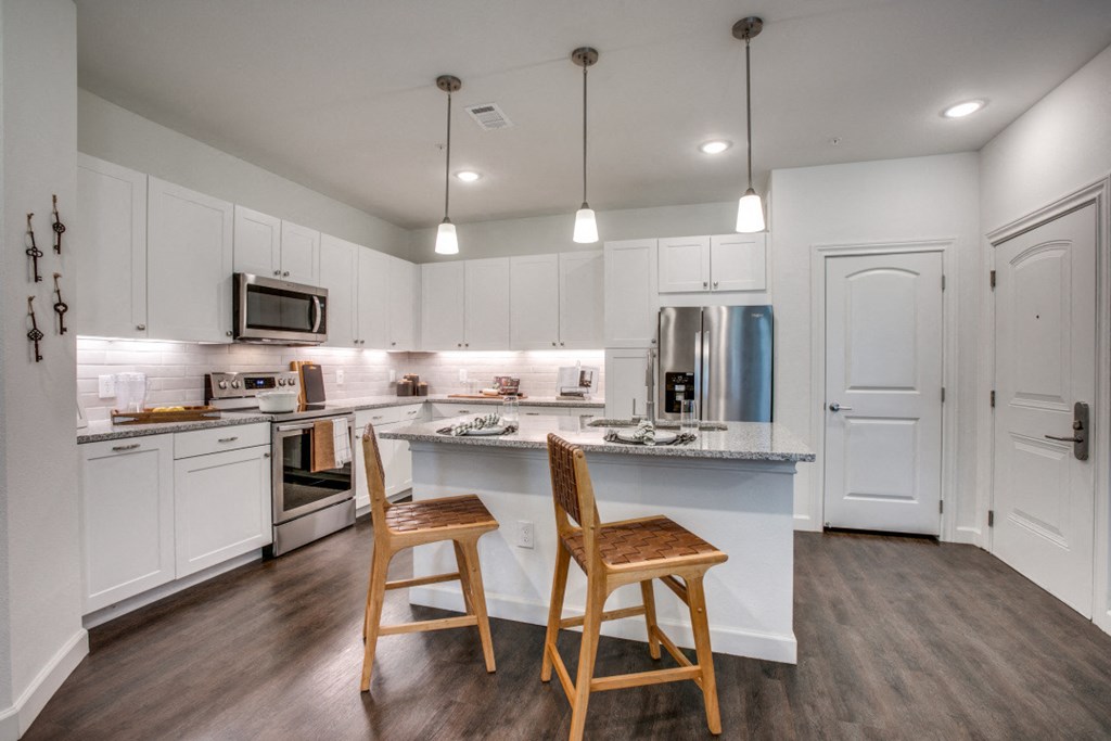 a kitchen with white cabinets and a large island with two stools