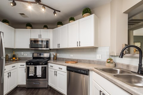 A modern kitchen with white cabinets and stainless steel appliances.