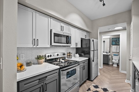 A modern kitchen with stainless steel appliances and a rug on the floor.