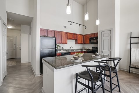 A kitchen with a black refrigerator and wooden cabinets.