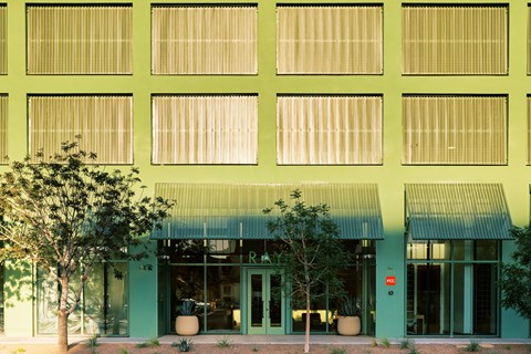 A building with green walls and a green awning with the letter R on it.