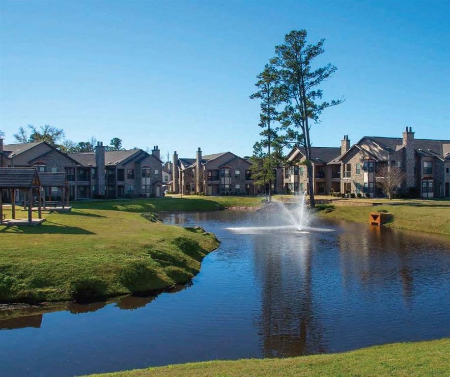 a fountain in the middle of a pond with houses in the background