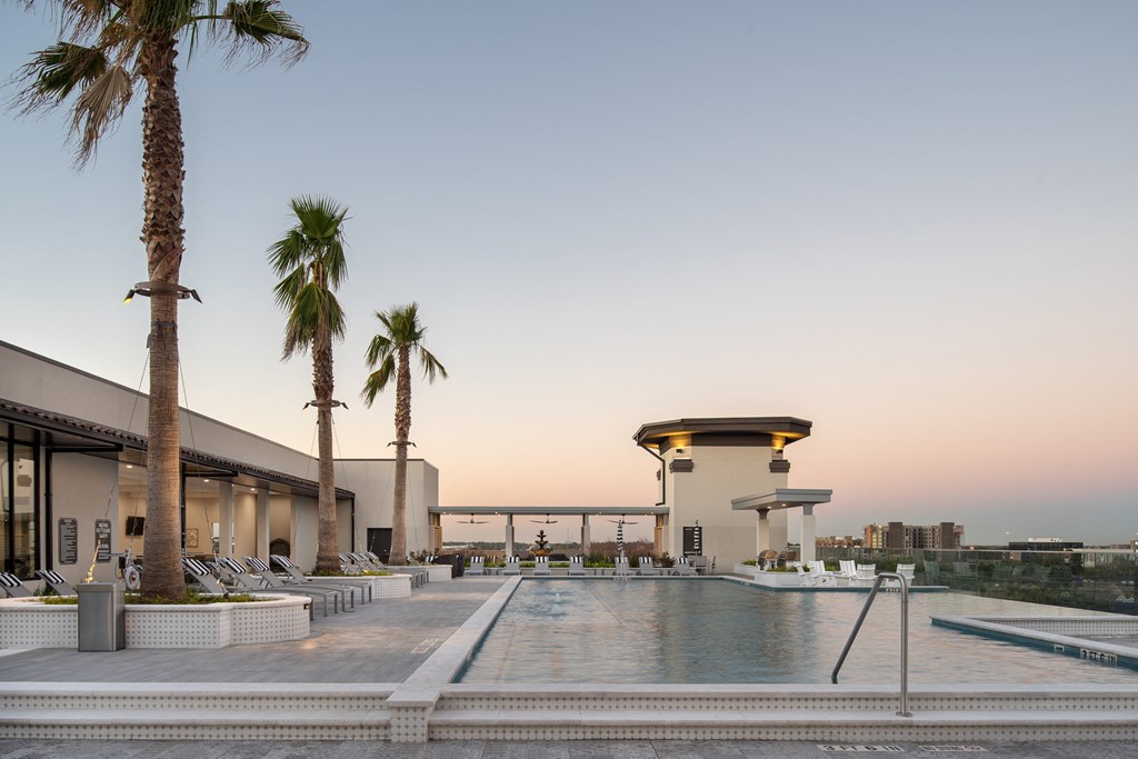 a hotel pool with palm trees and a building in the background
