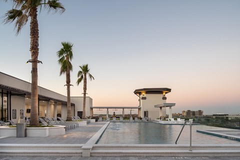 a hotel pool with palm trees and a building in the background