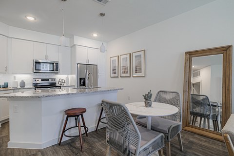 a kitchen with a breakfast bar and a dining room with a table and chairs