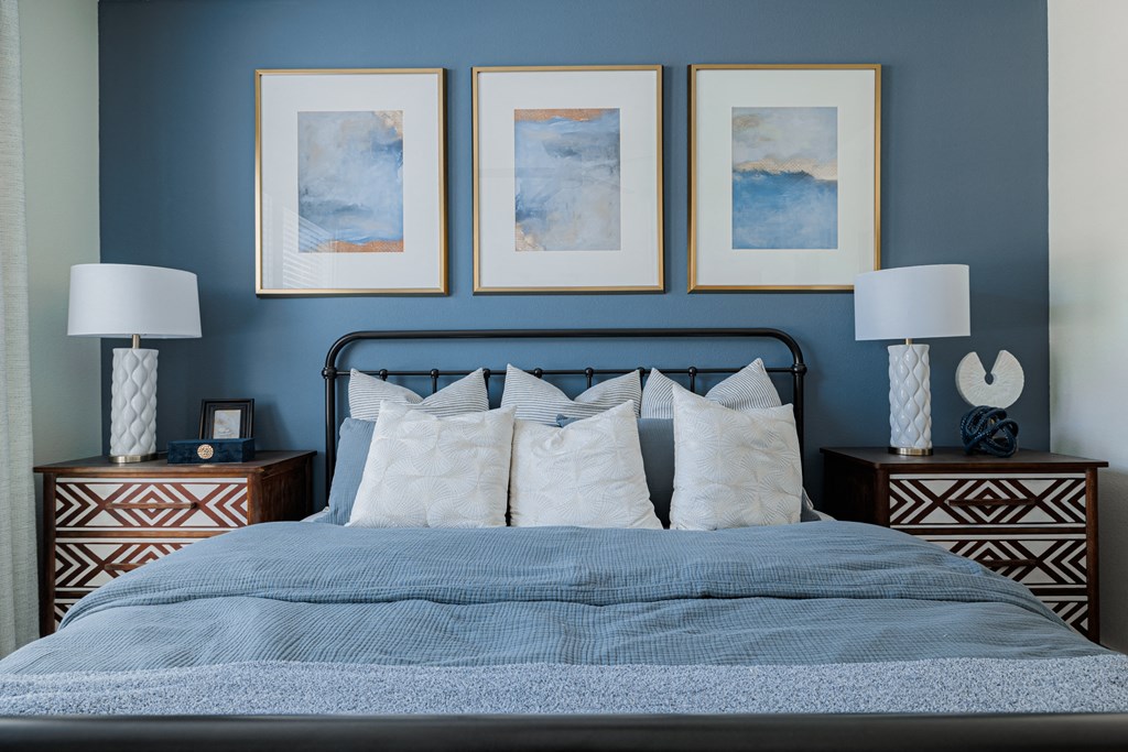 a bedroom with blue walls and three paintings on the wall